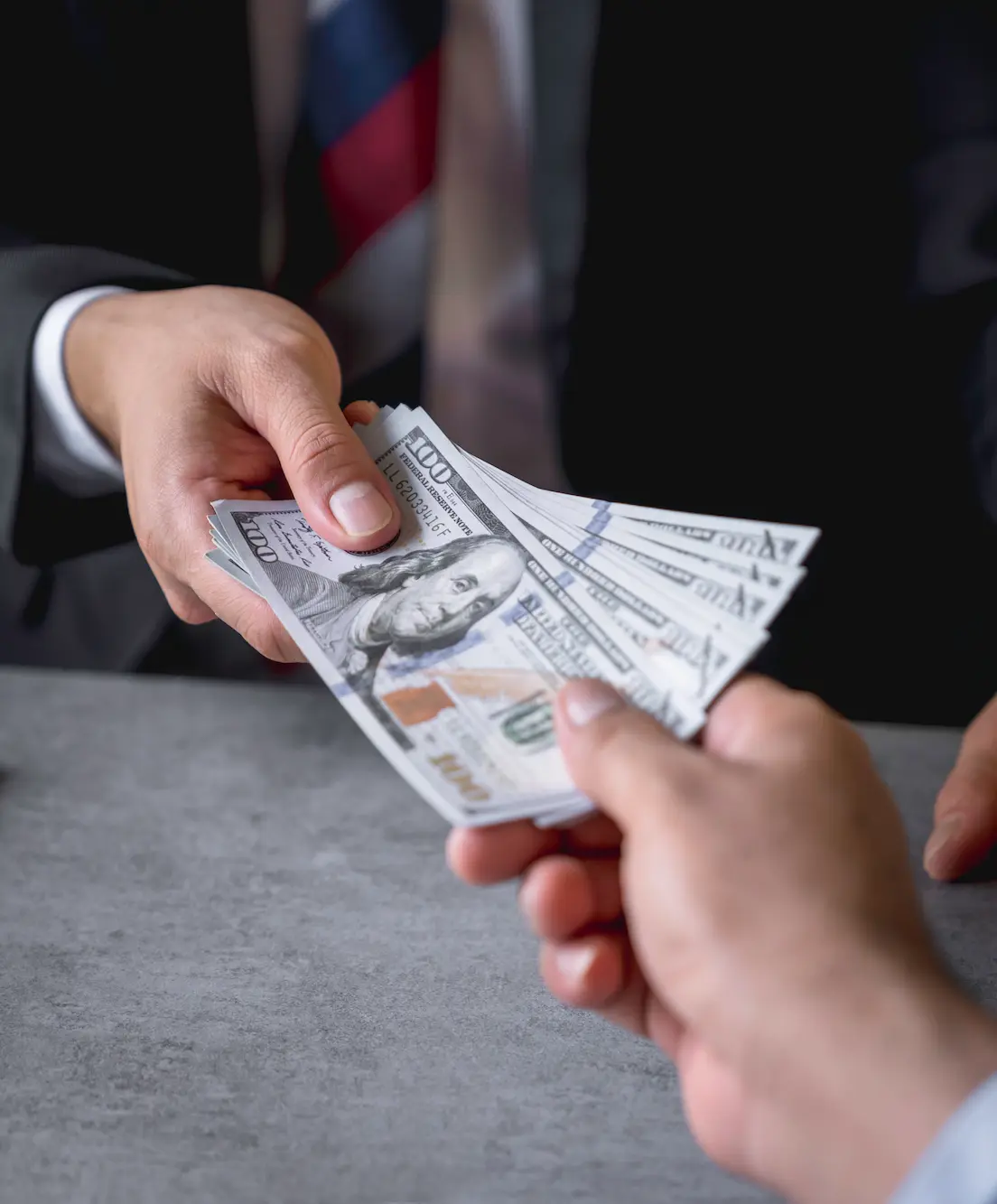 Manos intercambiando billetes representando las ganancias de una creadora en Fanvue